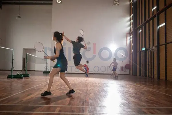 People jumping while playing badminton People jumping while playing badminton