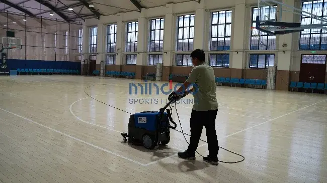 Workers cleaning and maintaining sports wood flooring Workers cleaning and maintaining sports wood flooring