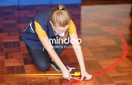 Installing competition lines on a wooden gymnasium floor Installing competition lines on a wooden gymnasium floor